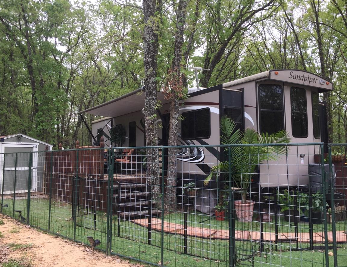 Full time RV living with deck, shed, fence, grass
